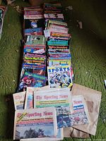 Stacks of assorted sports magazines and newspapers on green carpet