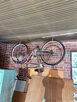 Full bicycle hanging upside down showing frame, wheels, and basket