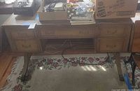 Front view of light brown wooden desk with four drawers and curved legs