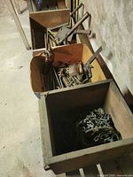 Cardboard box inside crate holding various hand tools; separate crate with metal chains