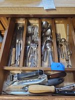 Drawer with assorted flatware and kitchen gadgets visible