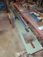 Overall view of tools on bench including shovel, coal scoop, pole, rods