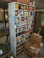 Front view of tall white wooden shelf cabinet loaded with cans (contents excluded)