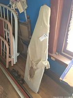 Full view of folded wooden ironing board leaning against wall