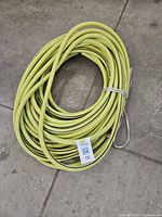 Coiled green-yellow rubber garden hose on floor