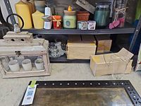 Overall lot showing wooden lantern, shelf of candles, boxes, glass votive bucket