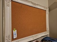 Front view of ornate cream framed cork bulletin board