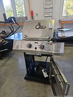 Front view of Char-Broil stainless steel two-burner propane gas grill with door open