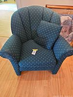 Front view of forest green floral shell back armchair with accent pillow