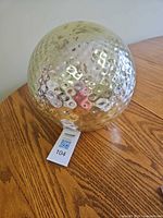 Front view of gold mercury glass sphere on wooden table