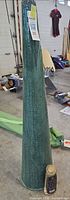 Full view of green cone-shaped ceramic tiki torch with lamp oil bottle at base