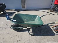 Full side view of green wheelbarrow showing frame, wheel, and handles