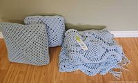 Two crocheted cushions and folded afghans showing motifs and colour