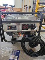 Front view showing Hyundai HD7250 generator, control panel, wheels, power cord, manuals