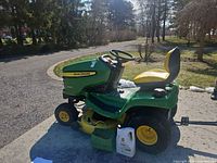 Left side view of John Deere X300 with mower deck, oil containers in foreground