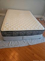 Full view of queen mattress on box spring showing quilted top