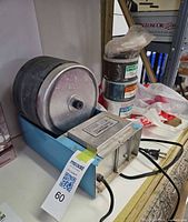 Front view of tumbler on base with stacked charge cans