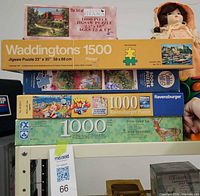 Stack of five jigsaw puzzle boxes showing fronts and side labels