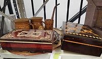 Two wooden marquetry boxes beside mugs and plates