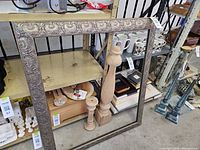 Large ornate embossed metal frame leaning against shelving