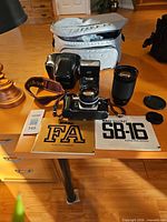 Group shot of camera body with 50 mm lens, flash, zoom lens, bag, strap, manuals, caps