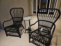 Two black wicker chairs and marble-top table outdoors on patio