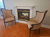 Pair of carved wood fireside armchairs in front of fireplace