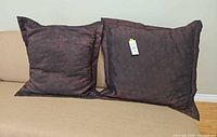 Front view of two brown quilted swirl throw pillows on couch