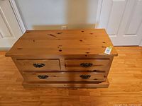 Front view of closed pine blanket chest with brass hardware