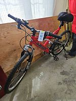Full view of red Supercycle Vortex mountain bike leaning against plywood