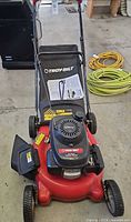 Front view of red Troy-Bilt mower with Honda engine, grass bag and manual on deck