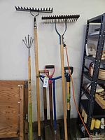 Group view of all long-handled tools leaning against wall