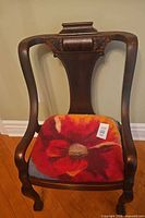 Front view of chair showing carved back, wood finish, floral felted wool seat