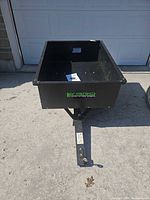 Full view of black steel dump cart with tow tongue extended