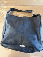 Full view of black Coach leather shoulder bag showing front and strap