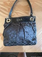 Front view of black Coach signature jacquard handbag
