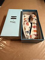 Shoes placed in open box with lid alongside