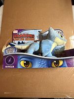 Front view of packaged Winger plush dragon