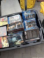 Overview of bin containing stacked DVDs and Blu-rays; visible titles Drive and Firewall