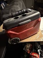 Full view of red IcyBreeze cooler showing logo, wheels, black lid with hose