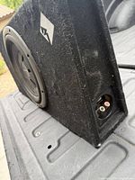 Front and side view of subwoofer in enclosure showing driver and terminal cup