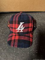 Front view of red navy plaid cap with white LA embroidery