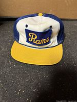 Front view of Rams snapback cap showing embroidered patch and brim colors