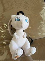 Front view of plush Mew backpack showing full figure and straps