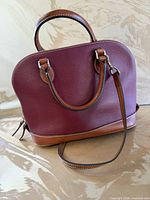 Front view of burgundy red Dooney & Bourke pebble leather satchel with tan trim and detachable strap attached