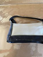 Front view of beige canvas and black leather Coach purse