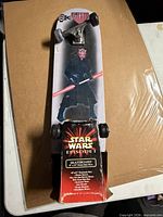 Top view showing grip tape with Darth Maul face, trucks and wheels, packaging on tail