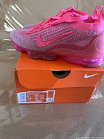 Side view of both shoes on original orange Nike box