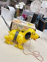 Yellow Slinky Dog pull toy standing in front of its box