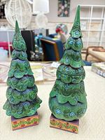Front view of both Jim Shore evergreen tree figurines showing painted details and relative sizes